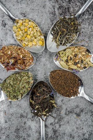 seven different spices and herbs on gray stainless steel spoons