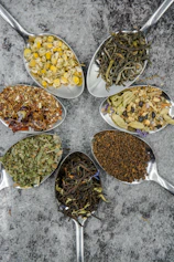 seven different spices and herbs on gray stainless steel spoons