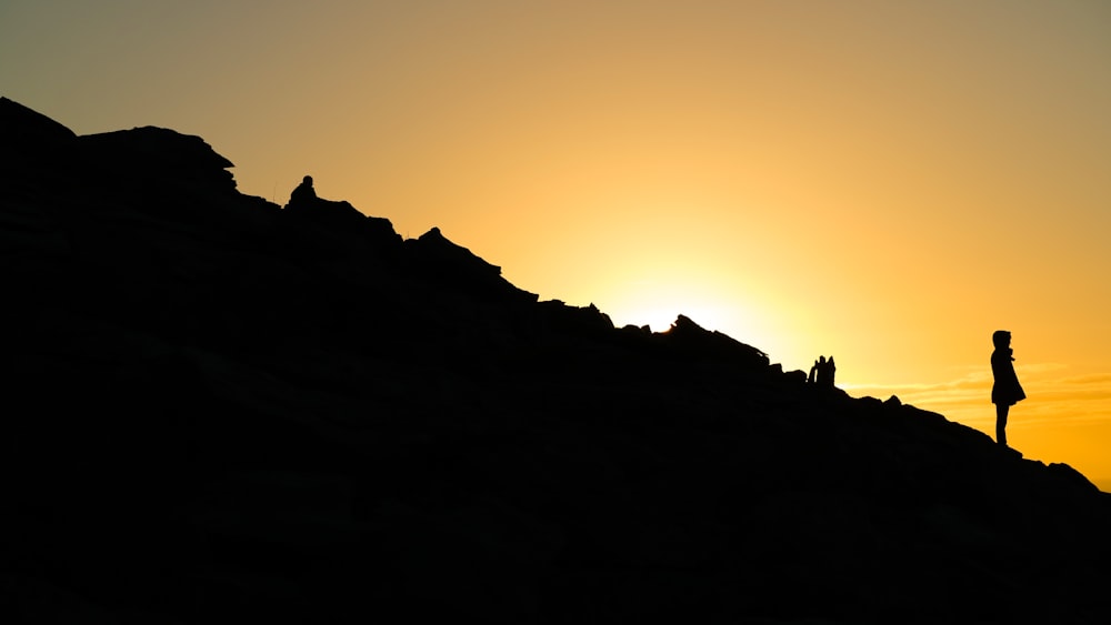 person standing on rocky mountain slope during sunset