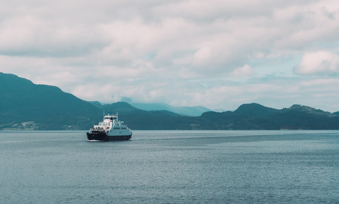 white boat sailing under cloudy sky