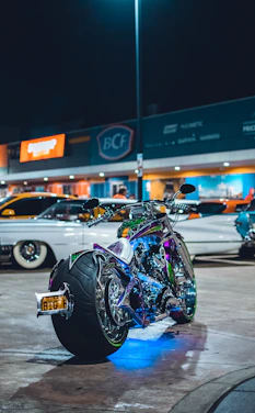 A neon-lit street at night with a custom modified bike parked under electric blue and safety orange lights.