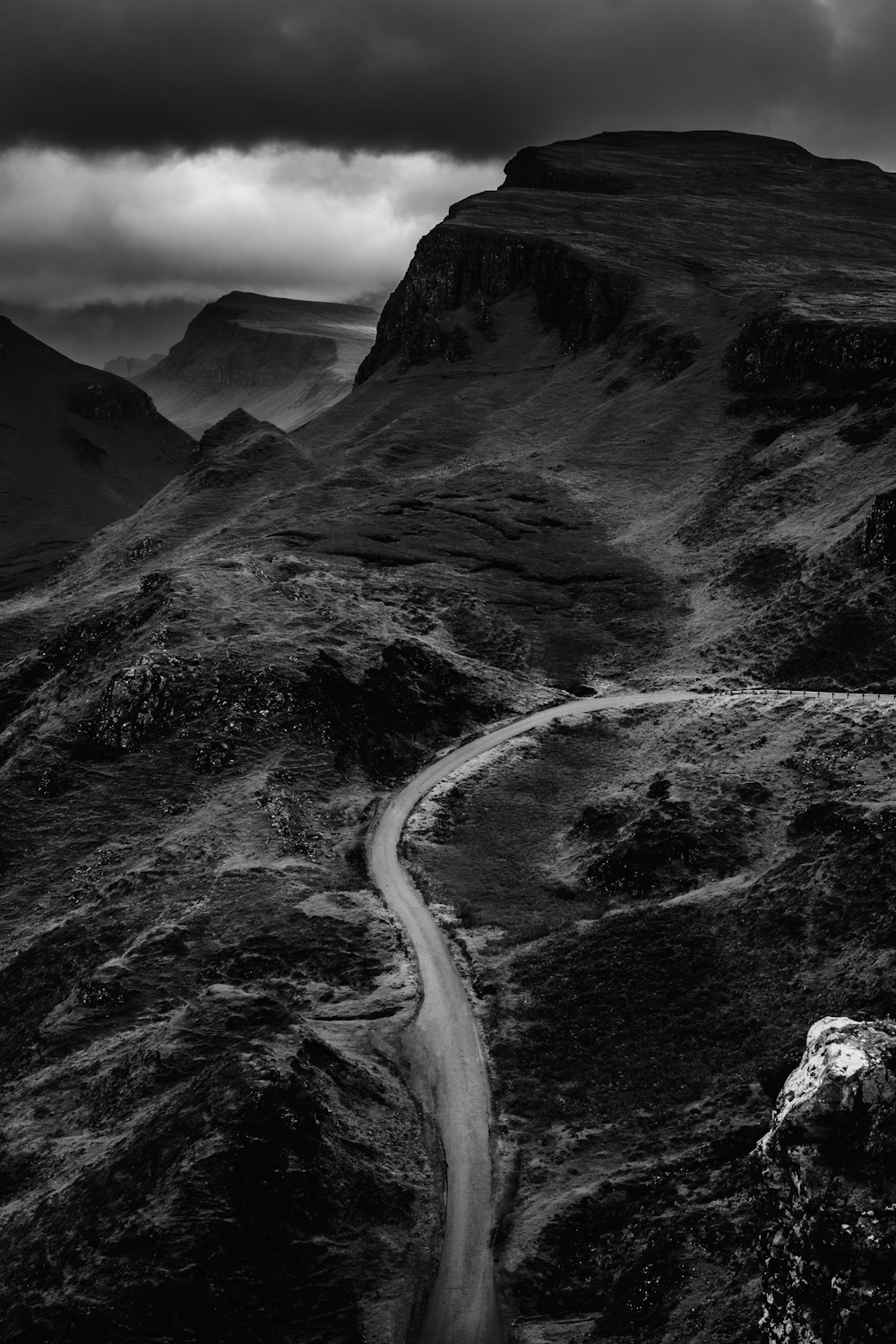 grayscale photo of road between mountain
