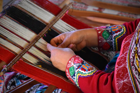 Close-up of artisans weaving intricate handloom fabric in a traditional workshop.