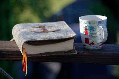 A sailor reading a waterproof nautical guidebook on a boat deck.