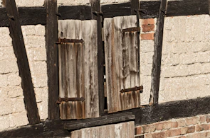 Close-up of restored wooden shutters with a smooth dark stain finish.