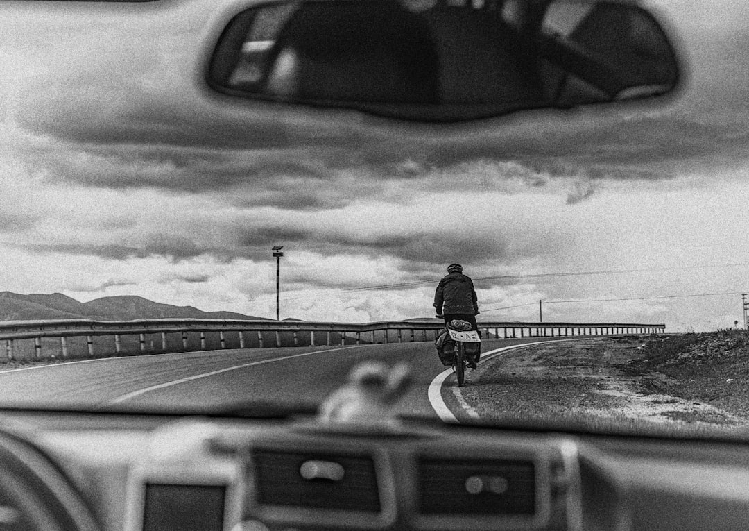vehicle traveling behind motorcycle on the road grayscale photography