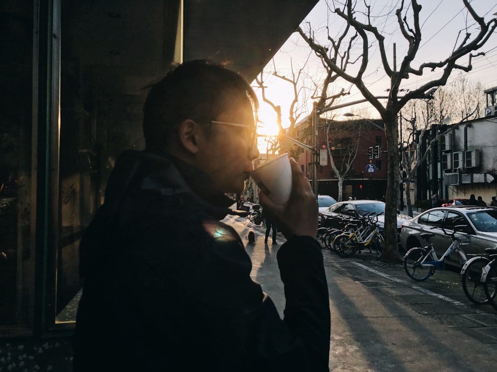 man in black jacket holding coffee cup