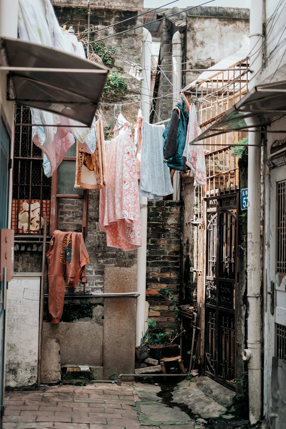 assorted clothes hanging on gray strings besides metal gate