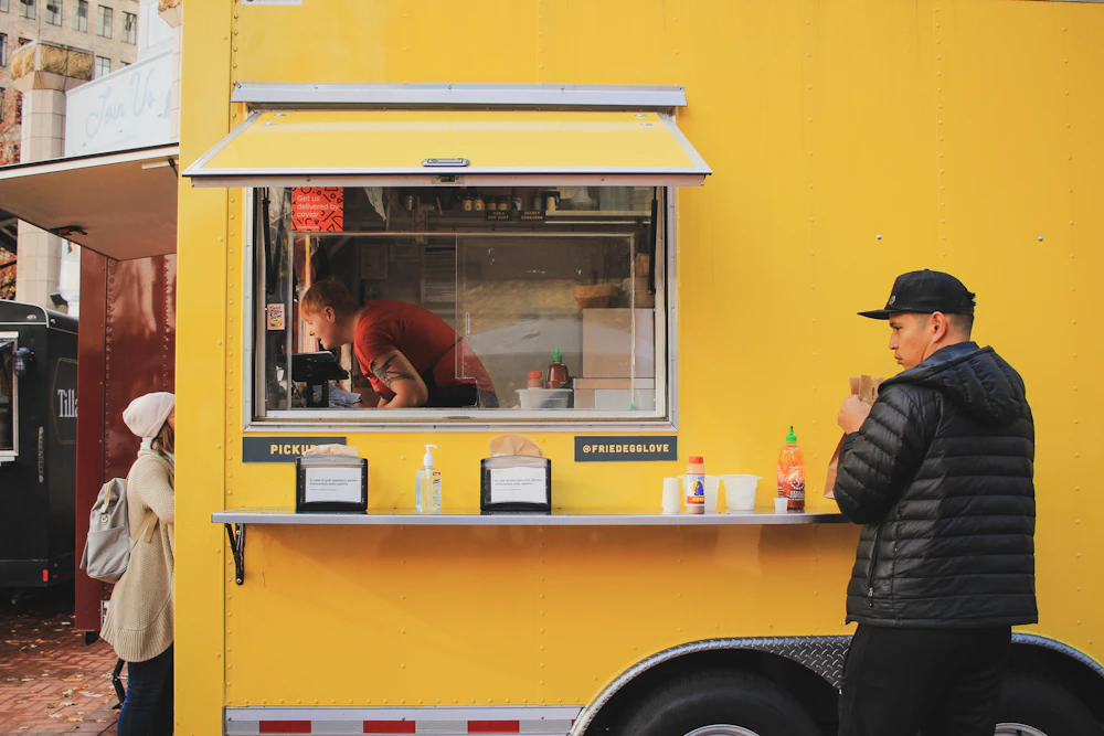 A customer in a heavy winter coat ordering at the open window of a food truck
