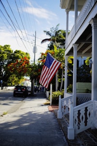 A warm, inviting photo of a classic Dallas neighborhood street in spring sunlight, showing local homes with Texas flags.