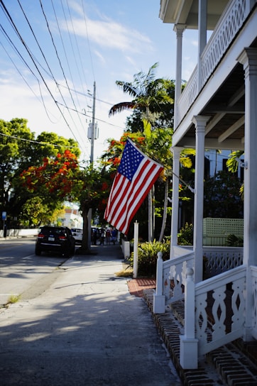 A warm, inviting photo of a classic Dallas neighborhood street in spring sunlight, showing local homes with Texas flags.