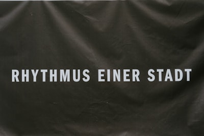 Text in bold white letters reads 'RHYTHMUS EINER STADT' on a dark background that appears textured or slightly crumpled.