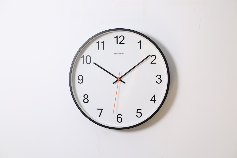 10:09 を指している円形のアナログ壁掛け時計