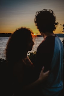 A couple enjoying a romantic sunset by a lake.