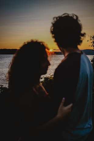 A couple enjoying a romantic sunset by a lake.