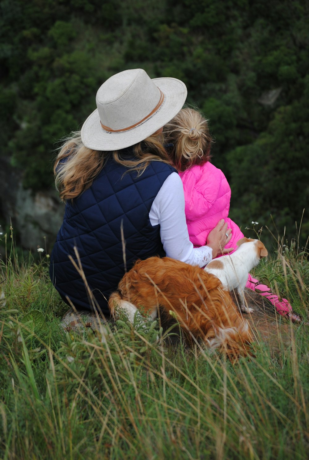 woman, girl and two dogs sitting on grass