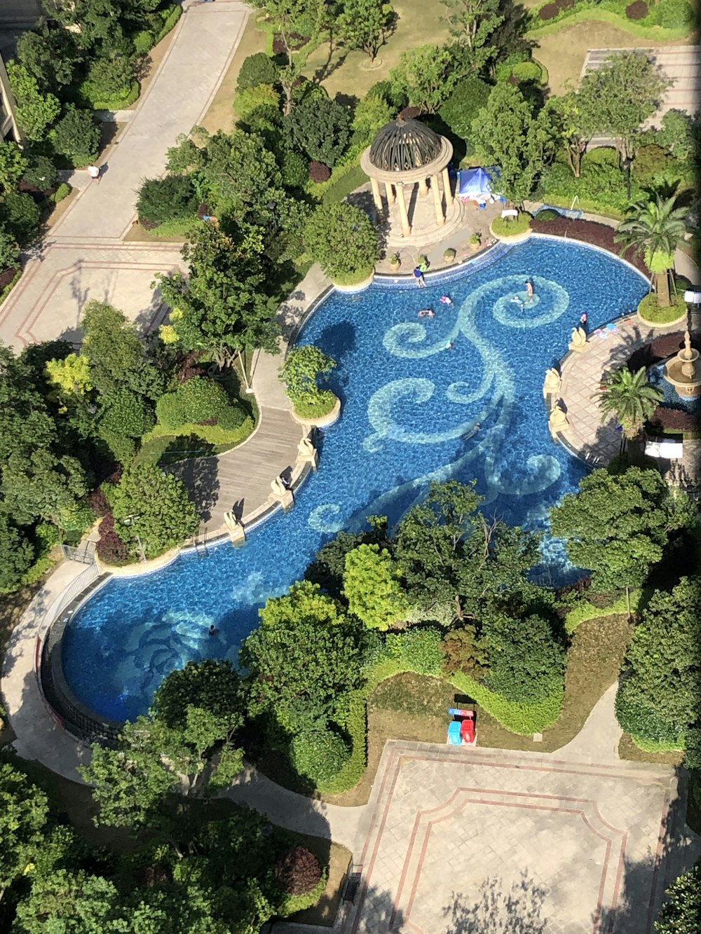 large blue and white pool surrounded by green trees at daytime