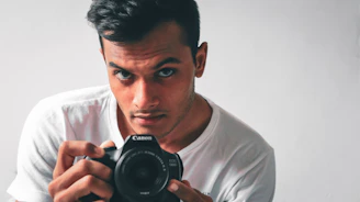 A friendly photographer holding a camera, ready to connect with clients.