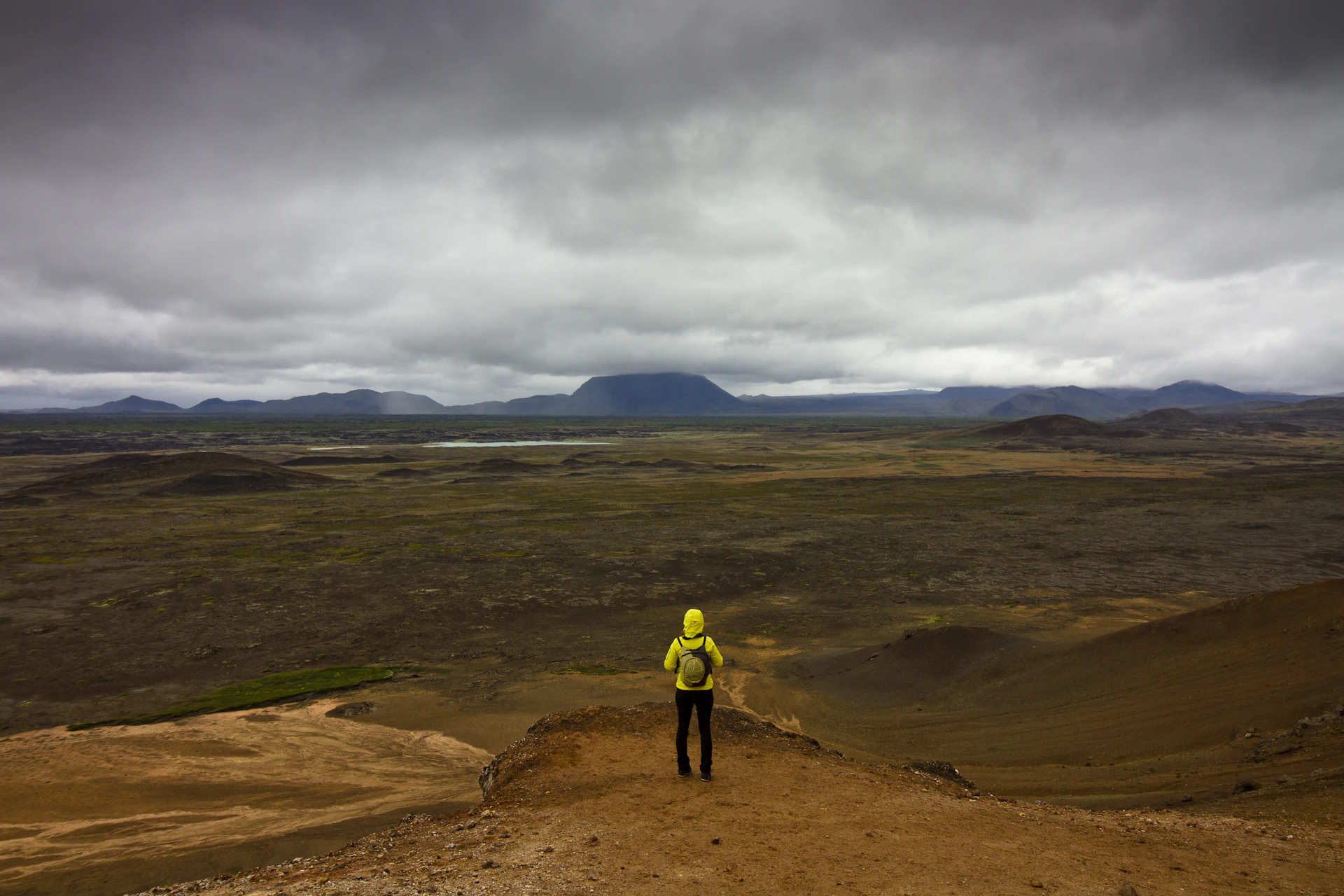 person in yellow hoodie standing on desert