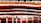A close-up view of layered translucent materials with vivid colors including red, orange, and white. The layers are interspersed with small bubbles and are stacked in an abstract, artistic manner. The surface reflects light, creating a vibrant and visually dynamic image.