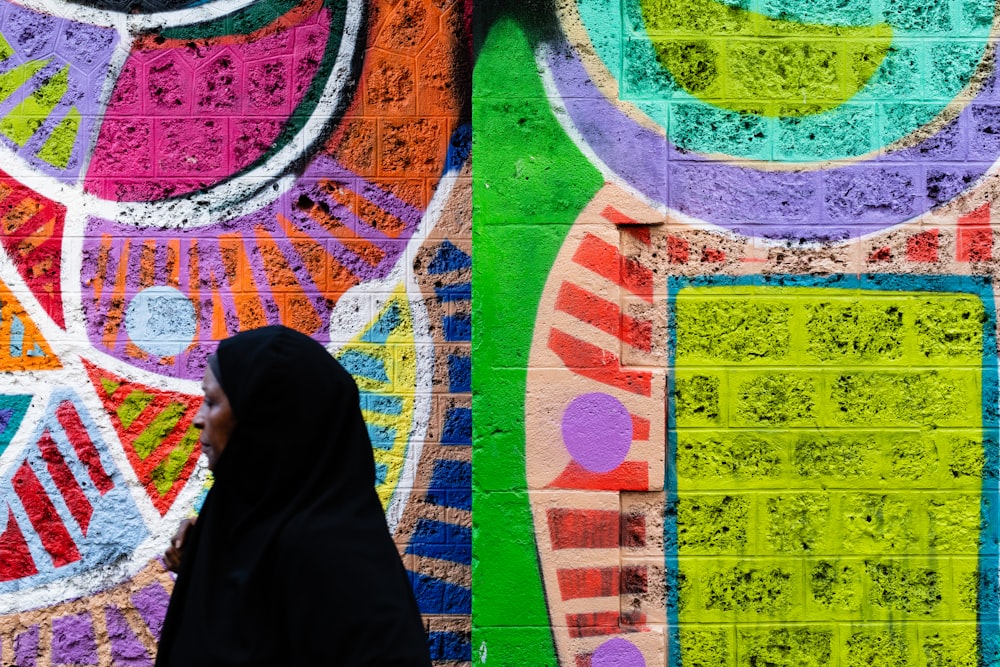 a woman walking past a wall covered in graffiti