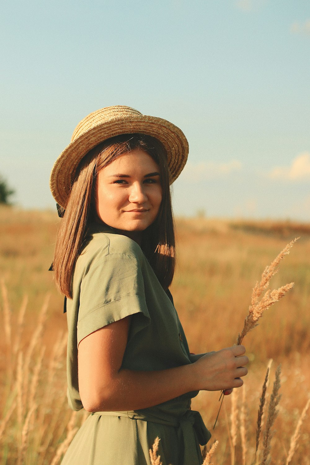 a woman in a hat standing in a field