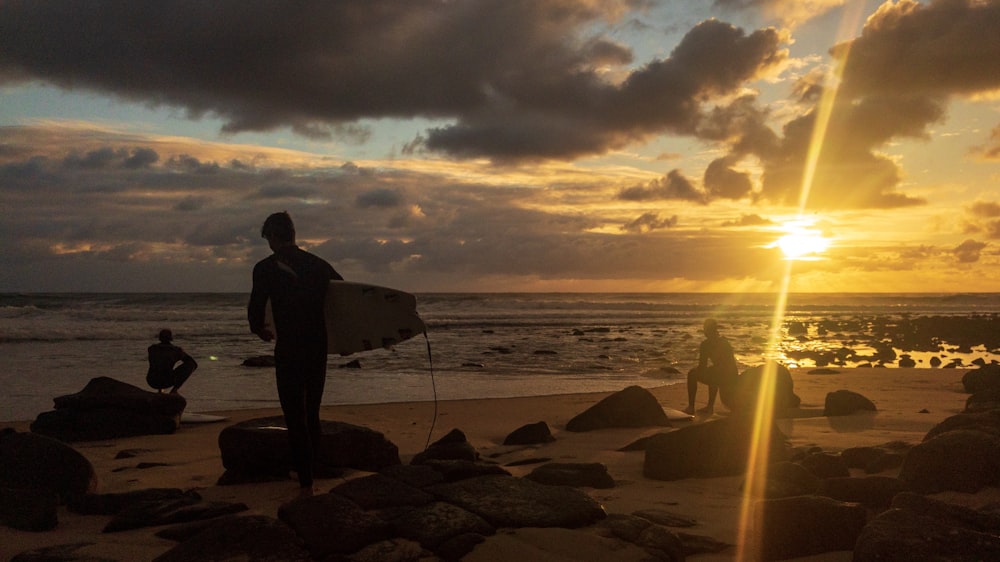 a man holding a surfboard on top of a sandy beach