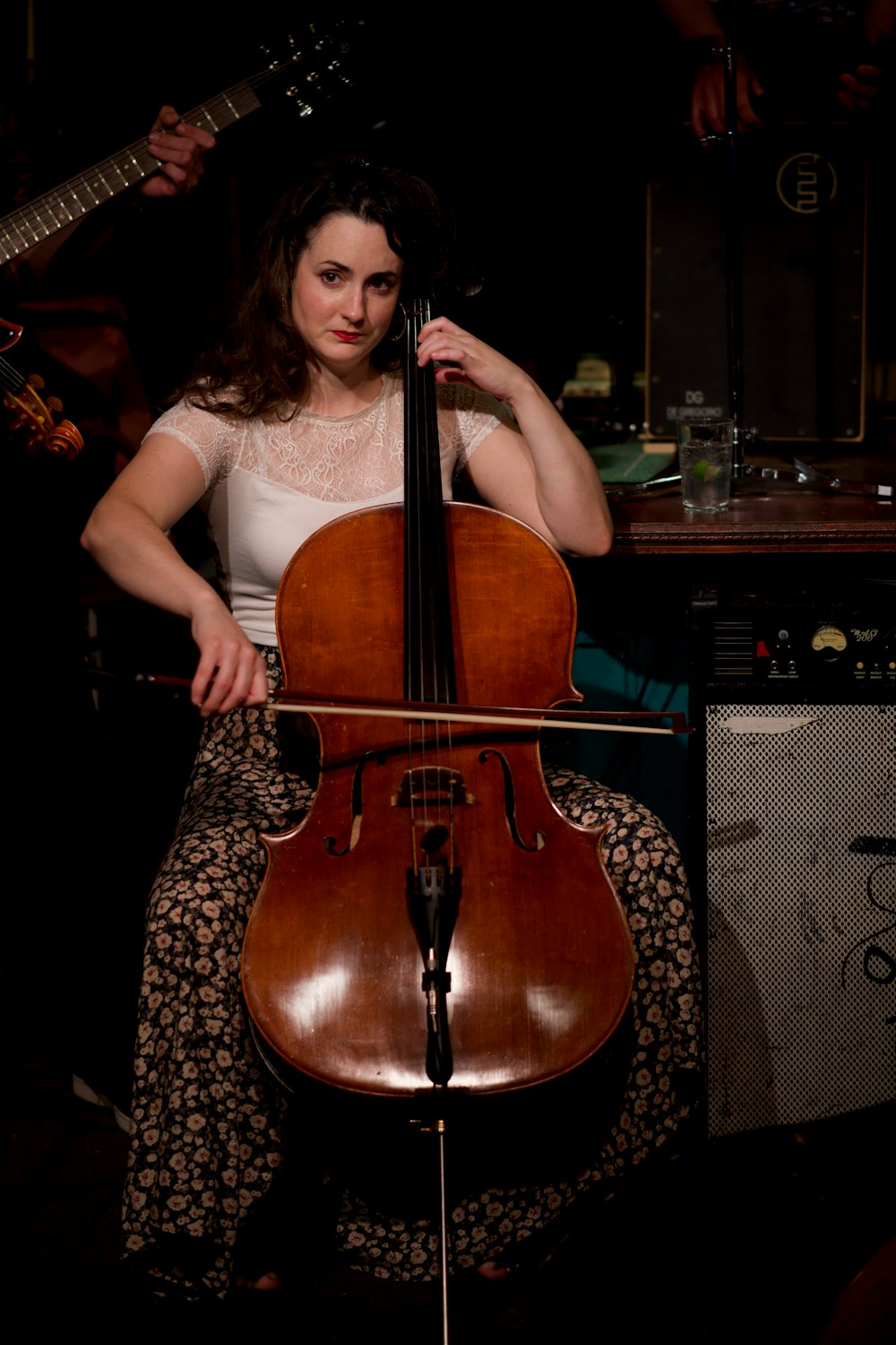 uma mulher sentada em um banquinho tocando violoncelo