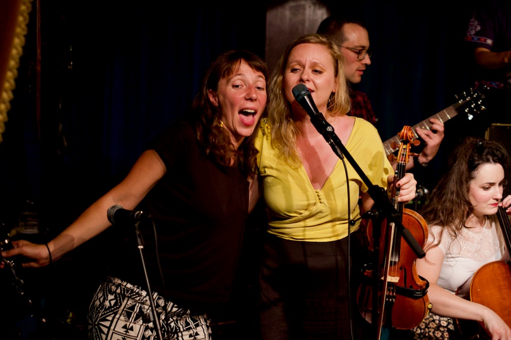 two women singing near microphone