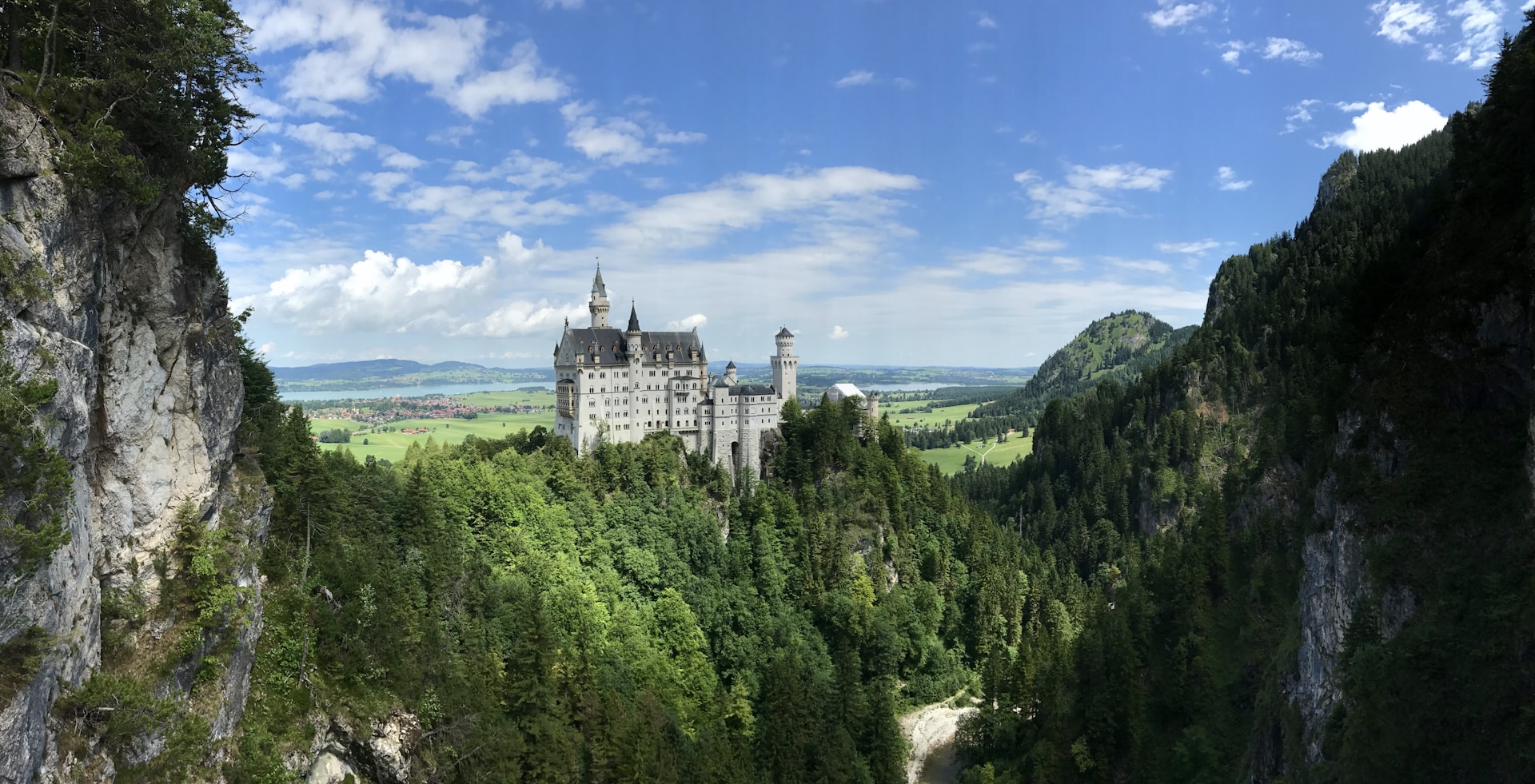 A majestic castle perched on a hill, surrounded by lush green forests and a clear blue sky.