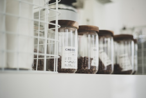 Rows of small glass jars filled with different coffee beans, labeled and lined up neatly.