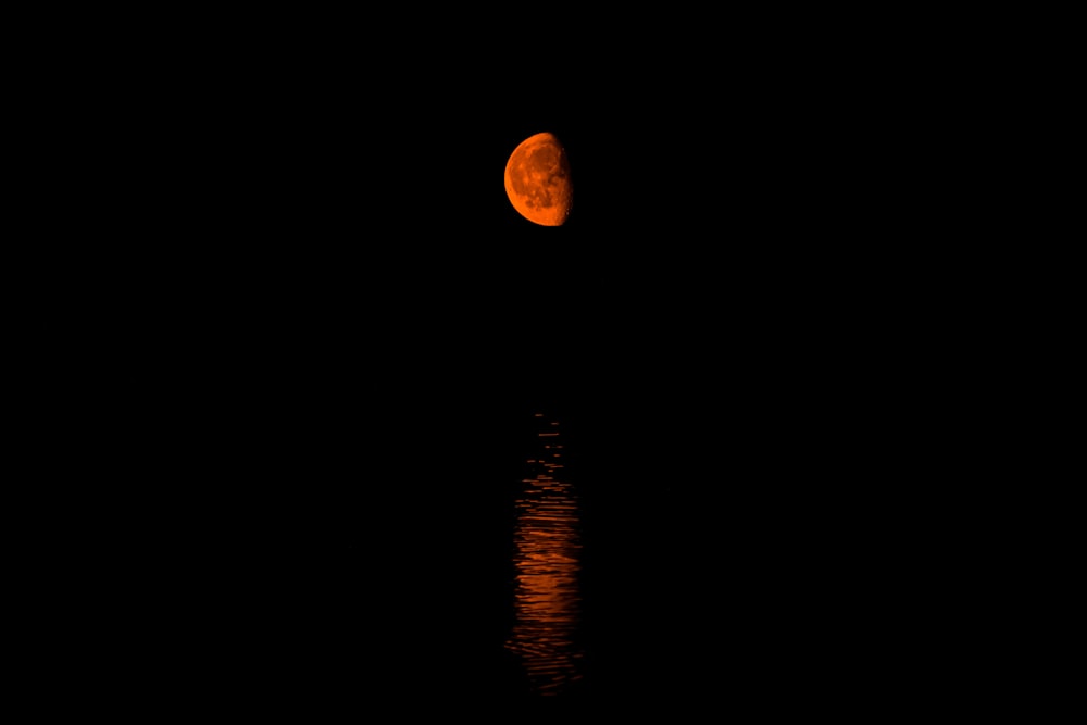 a full moon is reflected in the water