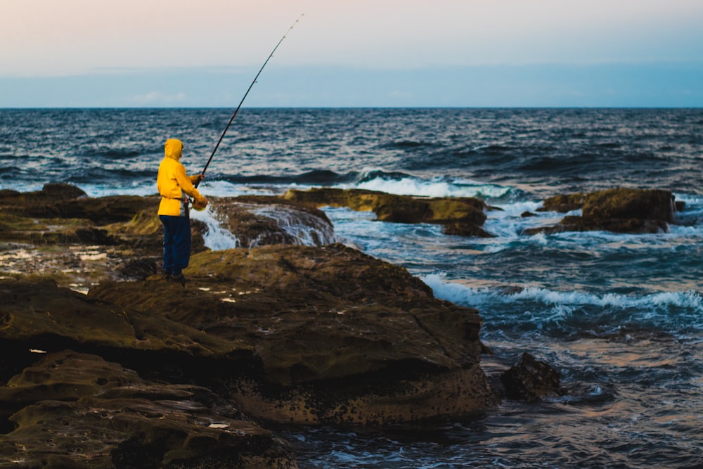 Persona in felpa con cappuccio gialla che pesca durante il giorno