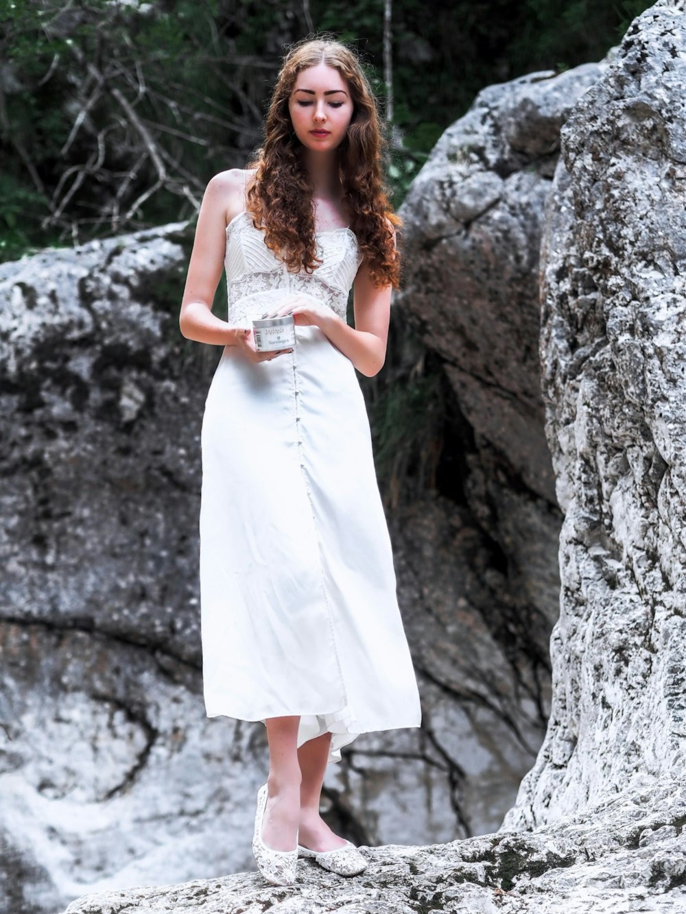 woman in white sleeveless maxi dress standing near rock