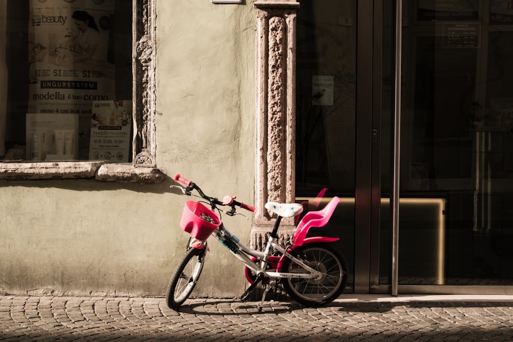 pink and gray training bike beside concrete house