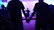 Volunteers holding hands in a circle with soft pink and purple lighting.