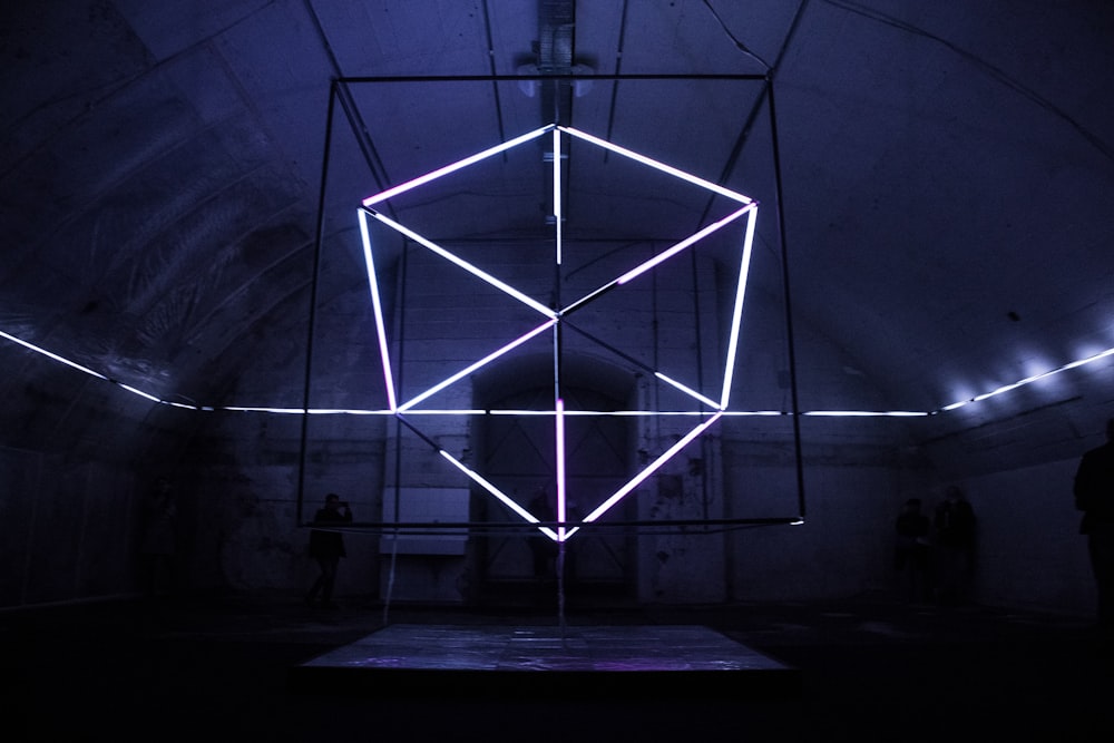 a neon cube in a dark room with people standing around