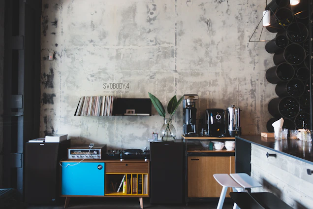 Interior view of a minimalist brutalist speakeasy with red accents and sleek hi-fi equipment.