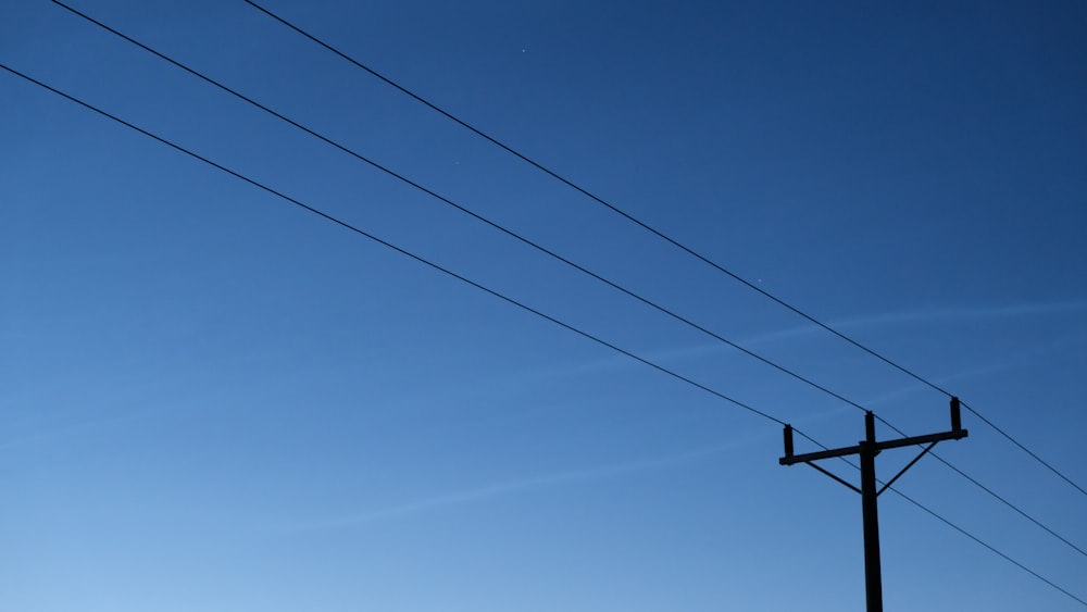a telephone pole and power lines against a blue sky