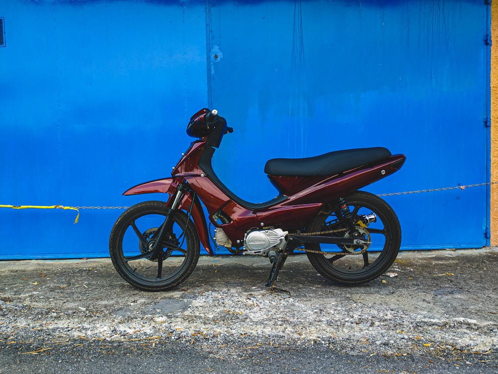 빨간 오토바이는 파란색 페인트 벽 옆에 주차되어 있습니다.