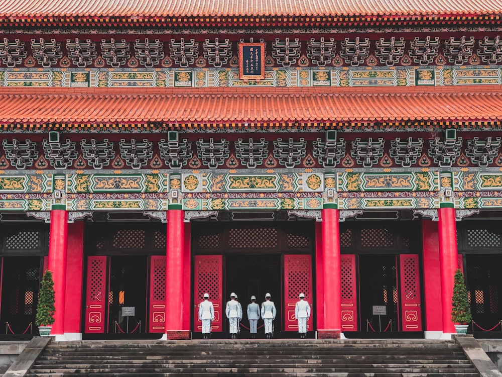 a group of people standing in front of a red building