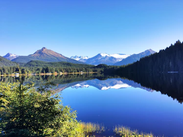 A pristine mountain lake reflecting clear blue skies and surrounding forest.