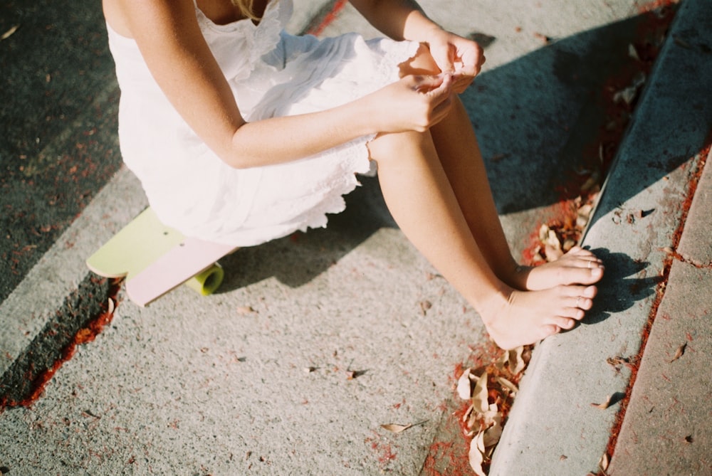 woman in white dress sitting on skateboard