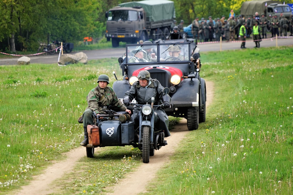 soldiers riding motorcycle with sidecar in front of truck on grass field