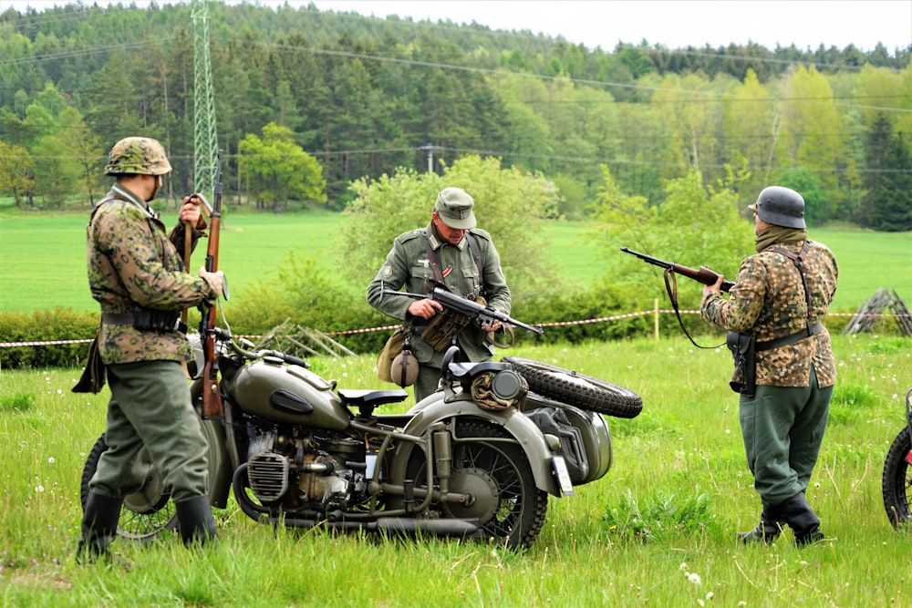 men holding rifles standing beside motorcycle with sidecar