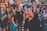 A group of enthusiastic people gathered together, appearing joyful and engaged in a lively event. Many individuals are smiling, singing, and raising their hands in celebration. The atmosphere is festive and vibrant.