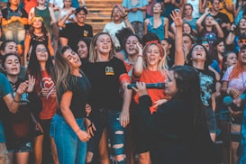 A group of enthusiastic people gathered together, appearing joyful and engaged in a lively event. Many individuals are smiling, singing, and raising their hands in celebration. The atmosphere is festive and vibrant.
