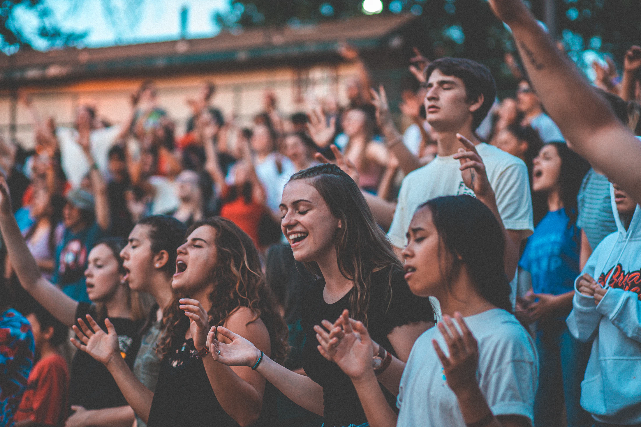 A crowd of young people gathered outdoors with their hands raised