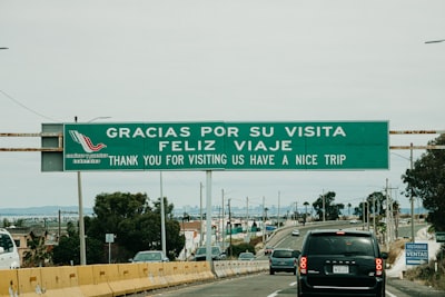 black vehicle on road with gracias por su visita feliz viaje signage