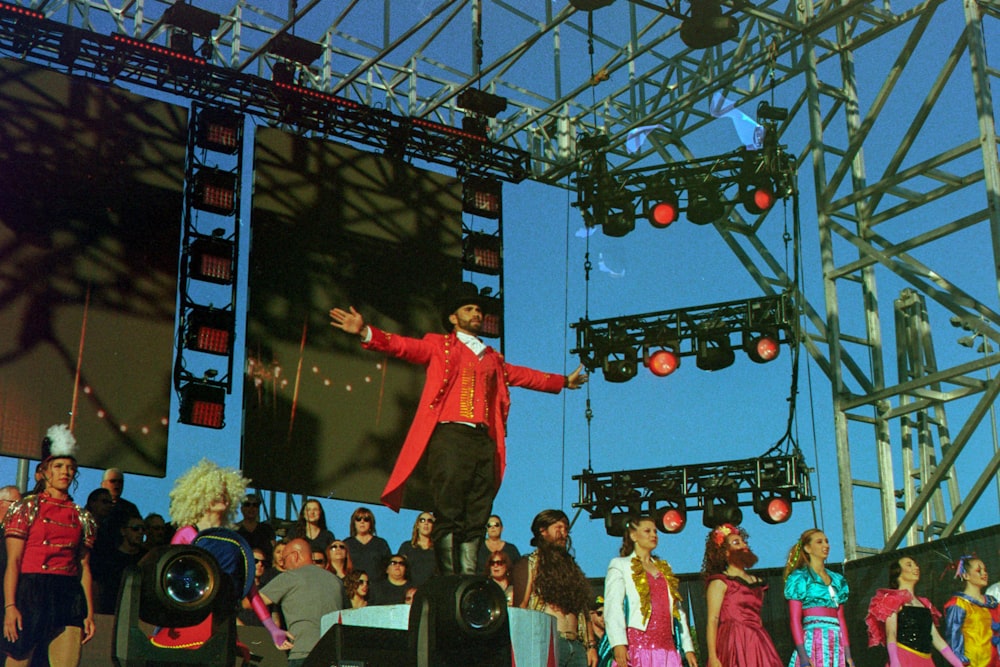 군중 앞에 서 있는 빨간 코트를 입은 남자